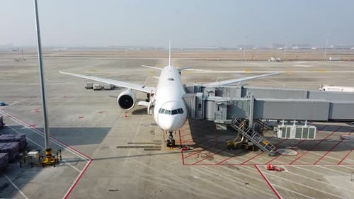White Commercial Airplane Parked At Gate Preparing For Passenger Boarding