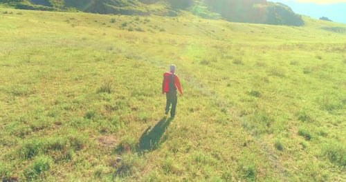 Flight Over Backpack Hiking Tourist Walking Across Green Mountain Field Huge Rural Valley at Summer