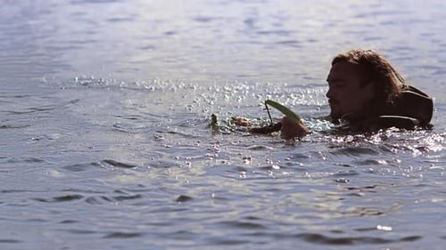 Young man in waterproof clothing prepares to wakeboard on a summer river