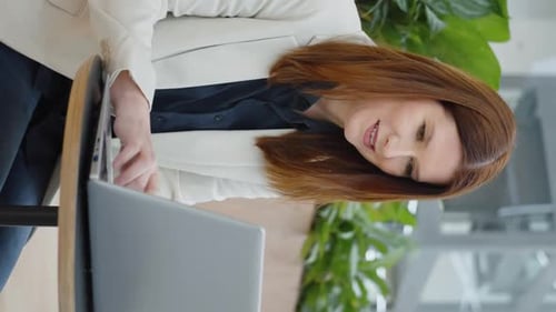 Vertical Screen: Businesswoman chatting online on laptop in cafe