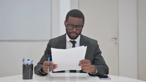 Thoughtful Businessman Reviewing Documents at office desk