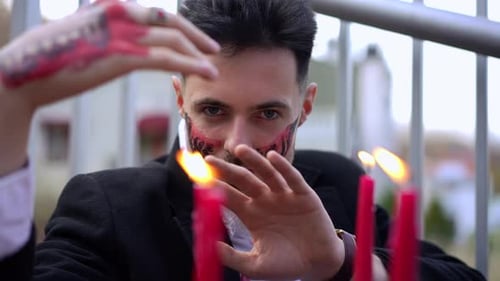 Dark-Haired Young Man Posing with Lit Red Candles