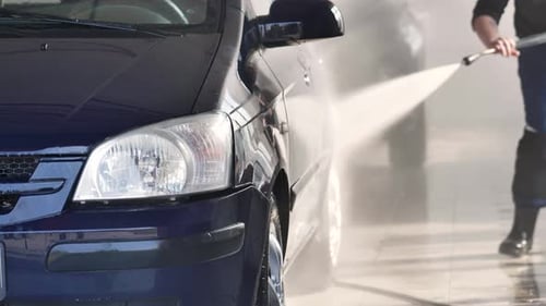A Closeup of a Car Headlight During a Car Wash