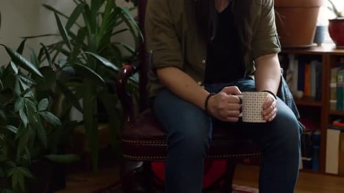 Thoughtful man with long hair drinking coffee indoors