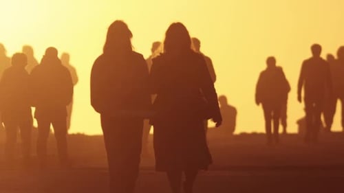 Silhouetted People Walking on Beach During Sunset