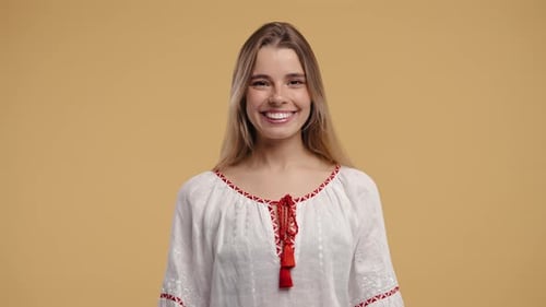 Smiling Woman in Embroidered Blouse Poses in Studio