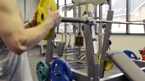 Young Muscular Man in Gym Lifting a Barbell on Bench