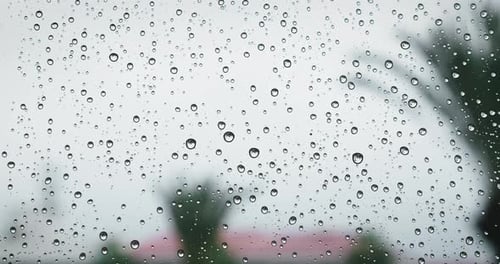 Rain Water Drops on Window Glass Closeup Blurred Outdoors View on Gray Overcast Sky and Street with