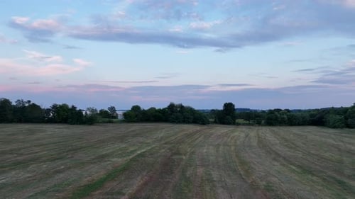 A low level aerial flight over a freshly mown hay field in the blue hour.