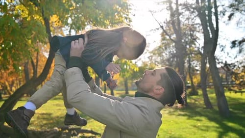 Happy family in an autumn park. Father lifted his daughter over his head. Slow motion