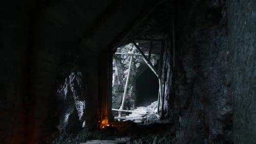 Dark Underground Mine Tunnel with Wooden Support Beams and Candlelight