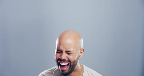 4k video footage of a young man laughing against a grey studio background