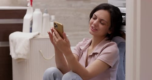 Woman Relaxing in Bathroom Using Smartphone Device