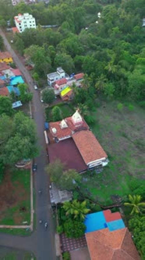 Vue prise par un drone de Devrukh, à Konkan, révélant une végétation luxuriante, des maisons éparpillées et une route sinueuse.