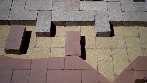 Construction zone detail of brick paver custom emblem in herringbone pattern.