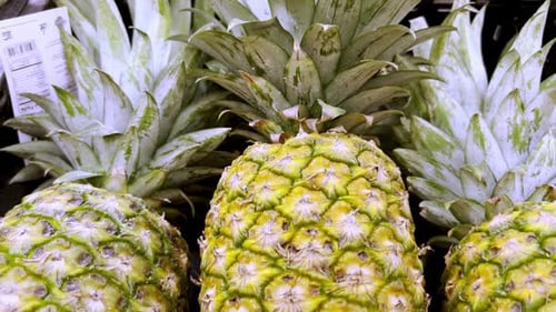 Zoom out of several pineapples arranged in a sales area.