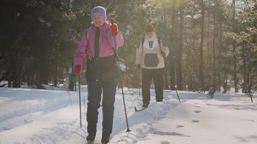 Energetic Senior Husband and Wife Skiing Together in Forest