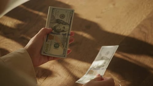 Hände zählen Hundert-Dollar-Scheine auf einem Holztisch