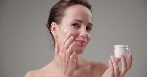 Woman Applying Cream to Face, Beauty Treatment