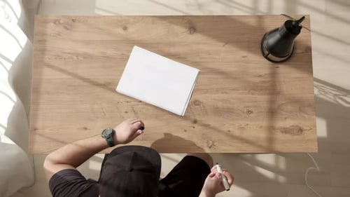 Man in Black Cap Sits Down at Table and Write Word START on White Sheet of A4 Paper with Black