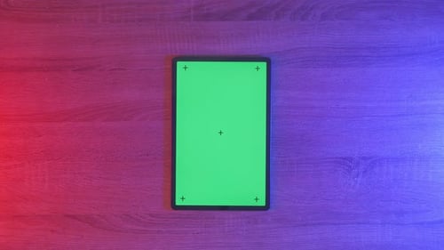 Top down view of a mock up green screen tablet on an neon desk, game concept