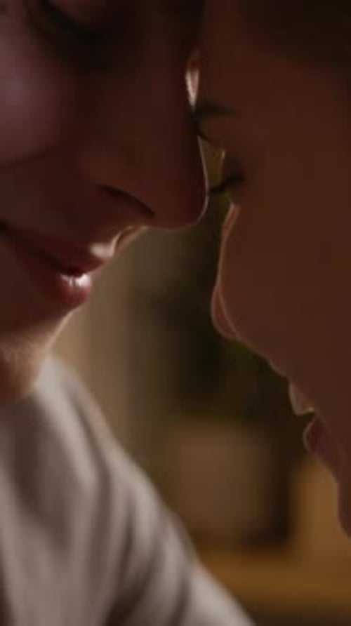 Vertical of Affectionate Couple Sitting Close and Sharing Kiss