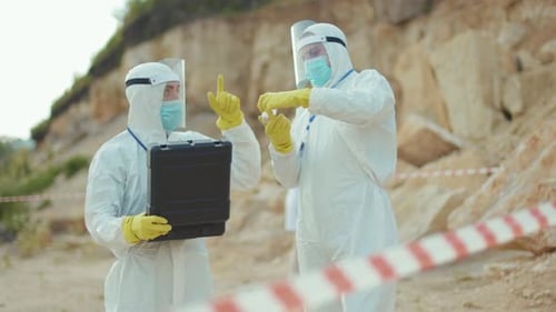 Scientists in Protective Suits Examine Samples Outdoors