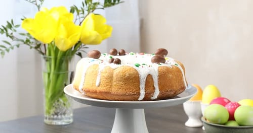 Köstlicher Osterkuchen, bemalte Eier und gelbe Tulpen auf Holztisch drinnen, Nahaufnahme