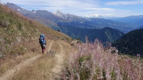 Backpacker hikes down hillside trail on rugged Caucasus Mountain trek