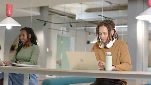 Des collègues afro-américains commencent à travailler, tapent sur des ordinateurs portables, vérifient leurs notes à une table partagée