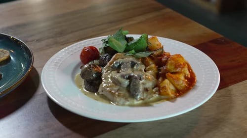 Delicious chicken dish recipe with mushroom cream, potatoes and salad on a restaurant table.