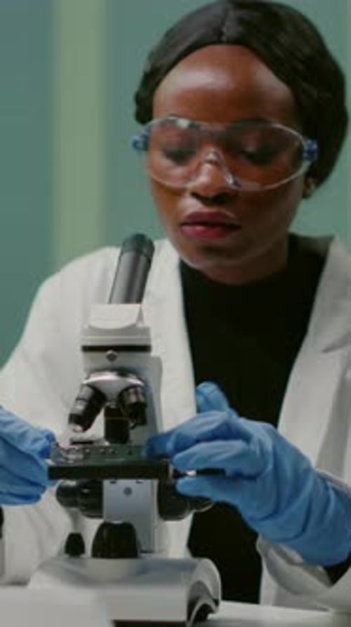 Woman Scientist Examining Sample with Microscope in Lab