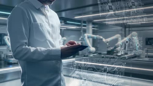 Engineer In Futuristic Electronics Assembly Factory Uses Tablet To Control Robotic Arms And Monitor