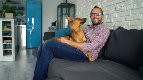 Man relaxing on sofa, petting his dog