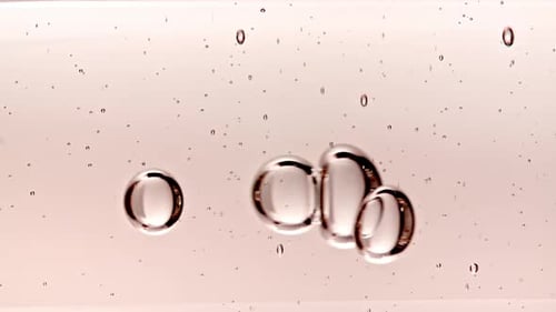 Gel cosmétique transparent avec bulles moléculaires et huile s'écoulant dans un tube en verre avec liquide transparent