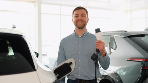 Man Holds Electric Vehicle Charging Cable in Showroom