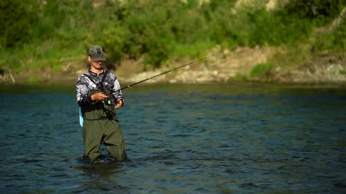 Man Fishing in River Wearing Waders and Hat