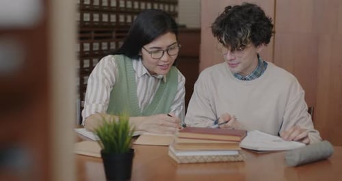 Girl and Guy Students Learning Together Reading Book Talking and Writing Preparing for College