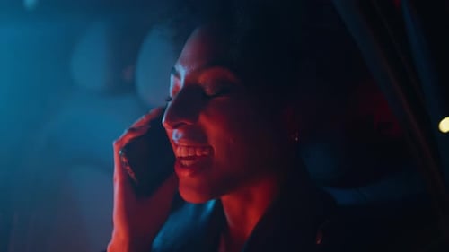 Smiling Woman Talking on Phone in Car at Night