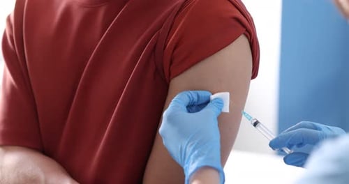 Nurse with syringe vaccinating man in hospital, closeup
