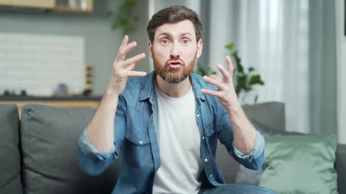 Webcam view of irritated arguing bearded man looking at camera yelling at online meeting at home