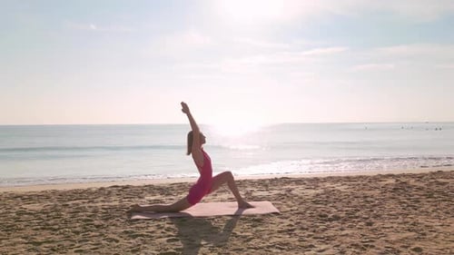 Woman Practicing Yoga on Sandy Beach at Sunrise with Ocean View