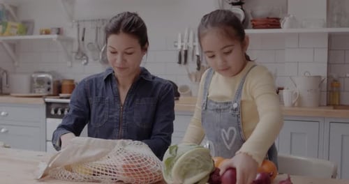 Woman and Child Unpacking Groceries in Kitchen