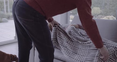 Femme mûre à la maison souffrant de fumée enveloppée dans une couverture sur un canapé avec un chien