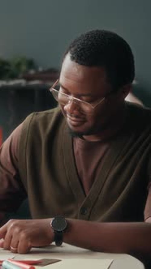 Vertical of Happy Black Man Writing on Christmas Greeting Card at Home