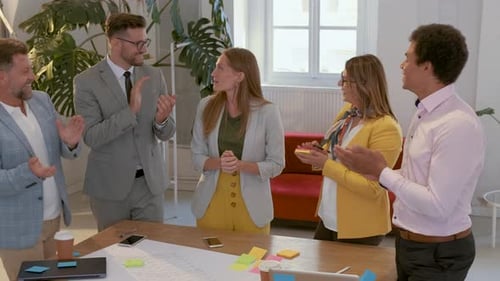 Group of business people applauding to female colleague in office.