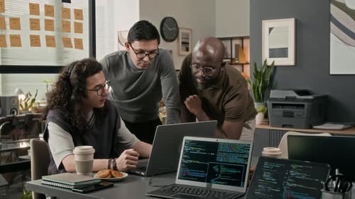 Three Men Collaborating on Code in an Office