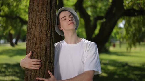Young Adult Hugging Tree in Green Urban Park