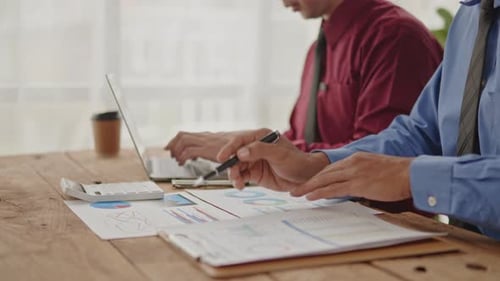 Des personnes travaillant de près travaillent et réfléchissent à des documents concernant les affaires, les finances et le marketing.