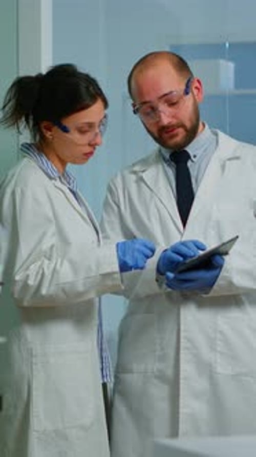 Scientists Discussing Data on Tablet in Bright Lab